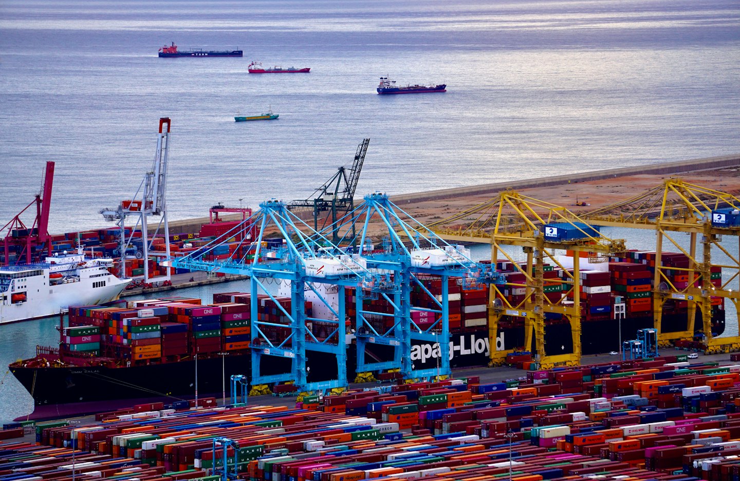 Cargo ships and containers at a busy shipping port.